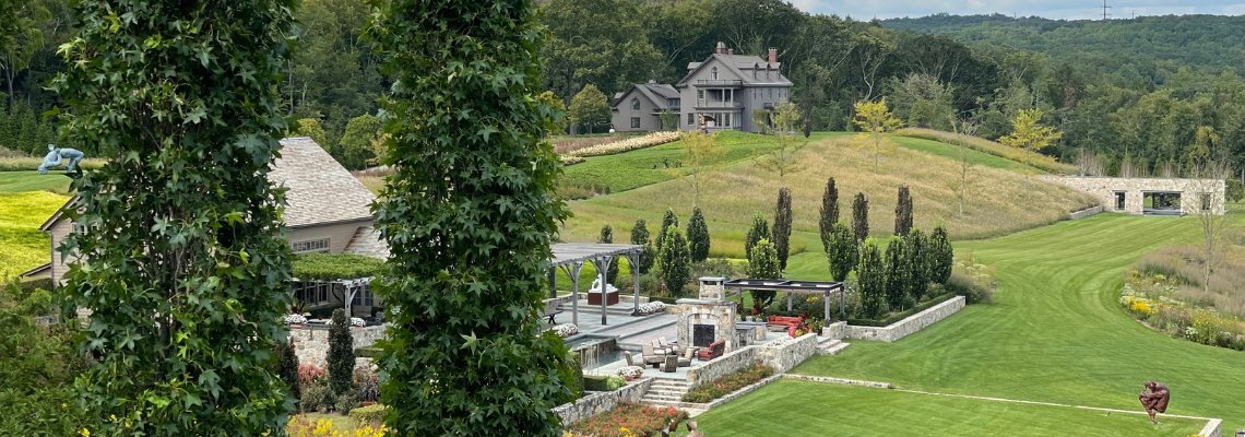 Wide view of InSitu in Redding, Connecticut with terraces, lawn, and hillside landscape
